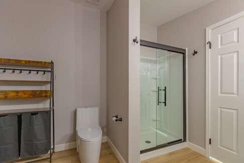 bathroom featuring a shower with door, wood-type flooring, and toilet