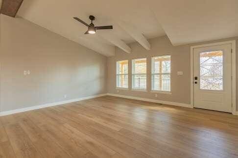 interior space featuring ceiling fan, light hardwood / wood-style flooring, and vaulted ceiling with beams