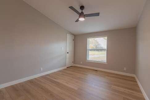 empty room featuring vaulted ceiling, light hardwood / wood-style floors, and ceiling fan