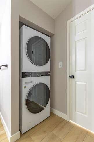 washroom with light hardwood / wood-style flooring and stacked washer / dryer