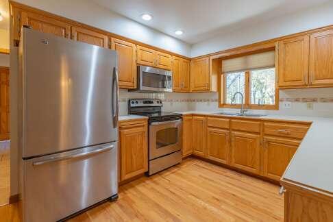 kitchen with brown cabinetry, appliances with stainless steel finishes, light countertops, light wood-type flooring, and a sink