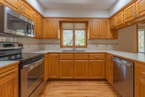 kitchen with light countertops, appliances with stainless steel finishes, brown cabinetry, and a sink