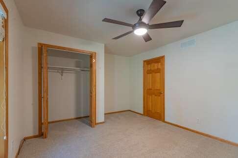 unfurnished bedroom featuring baseboards, visible vents, a closet, and light colored carpet