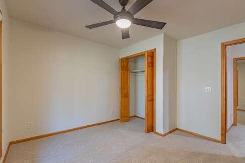 unfurnished bedroom featuring a closet, light colored carpet, ceiling fan, and baseboards