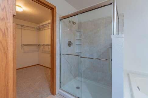 full bathroom featuring a shower stall and a walk in closet