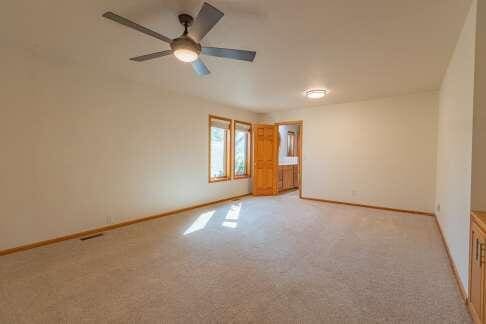 spare room featuring baseboards, a ceiling fan, and light colored carpet