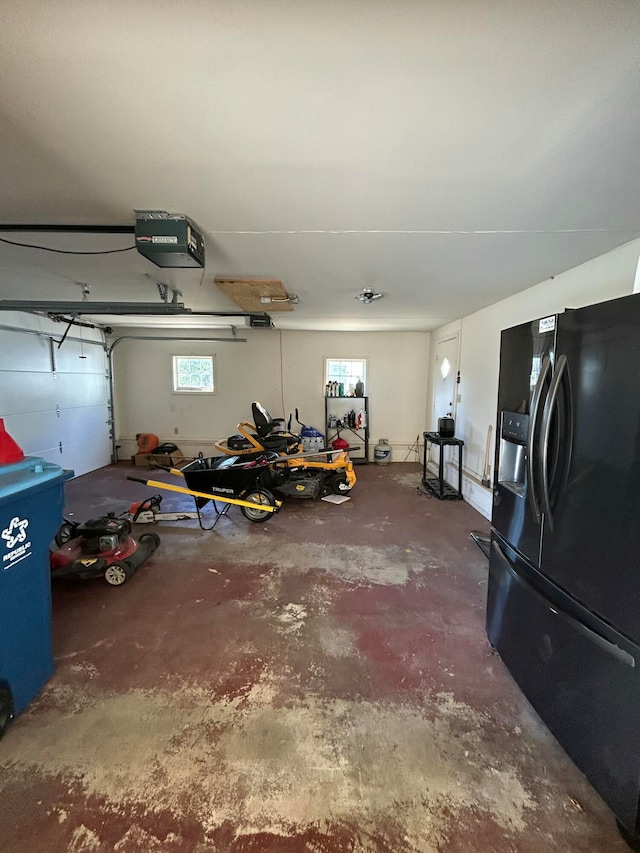 garage featuring black refrigerator with ice dispenser and a garage door opener