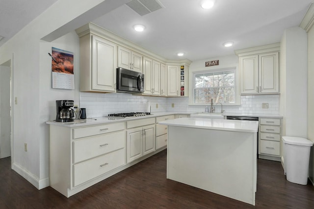 kitchen featuring sink, stainless steel appliances, dark hardwood / wood-style flooring, decorative backsplash, and a kitchen island