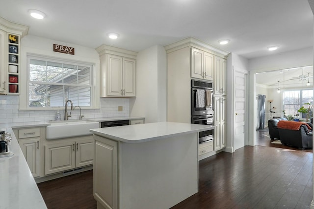 kitchen with sink, dark wood-type flooring, tasteful backsplash, double oven, and a kitchen island