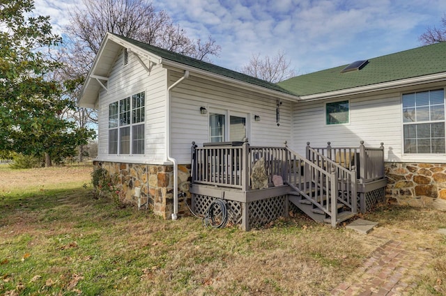 rear view of property featuring a deck and a lawn