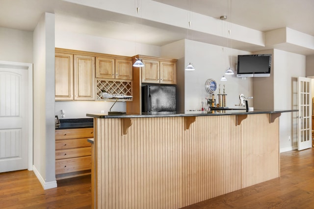 kitchen with black fridge, a breakfast bar area, and dark hardwood / wood-style floors