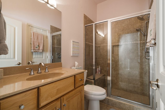 bathroom featuring a shower with door, toilet, and vanity