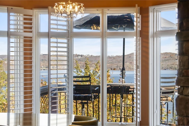 doorway to outside with a water view and an inviting chandelier