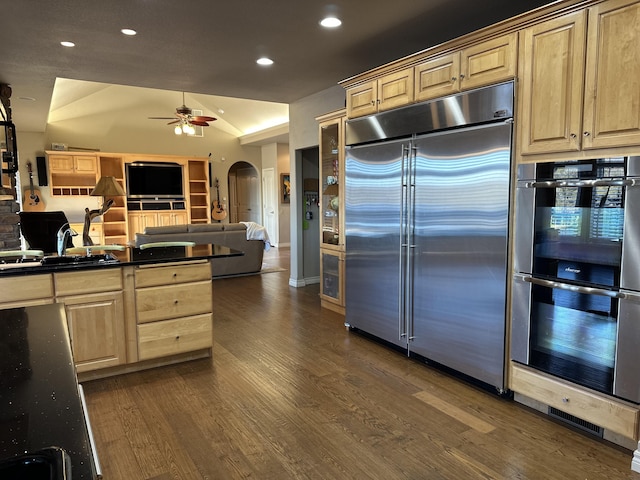 kitchen with ceiling fan, lofted ceiling, stainless steel appliances, dark hardwood / wood-style floors, and light brown cabinets