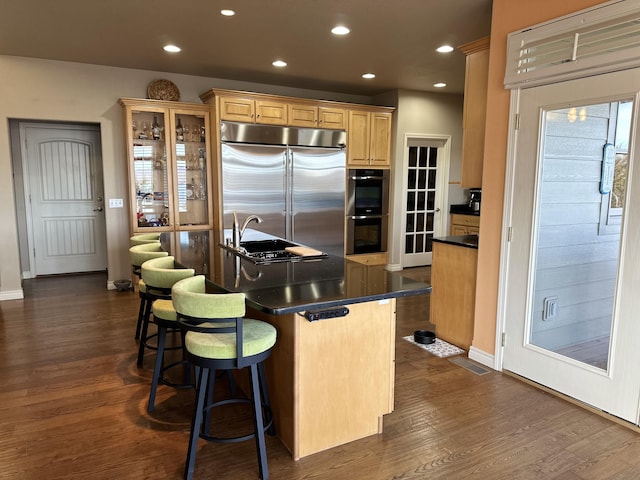 kitchen featuring light brown cabinets, dark hardwood / wood-style flooring, sink, a breakfast bar, and stainless steel appliances