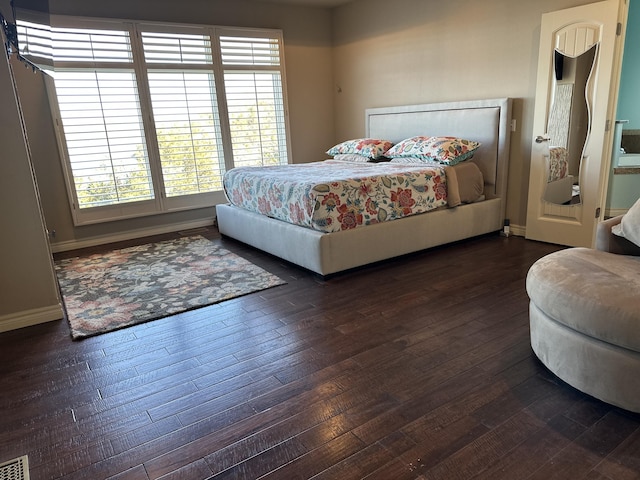 bedroom with multiple windows and dark hardwood / wood-style floors