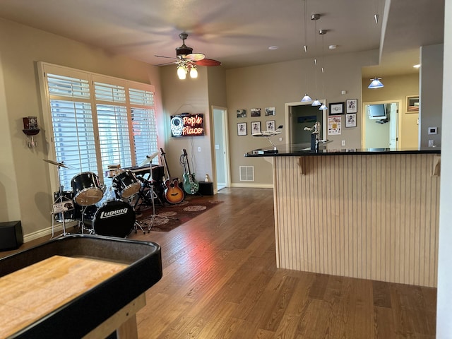 kitchen with hardwood / wood-style flooring, hanging light fixtures, a kitchen breakfast bar, kitchen peninsula, and ceiling fan