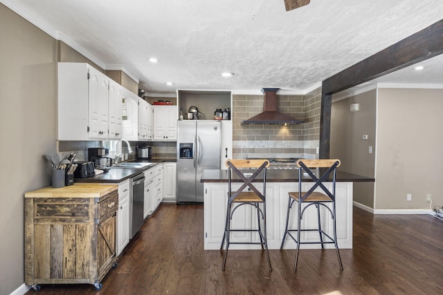 kitchen featuring white cabinetry, sink, a kitchen bar, stainless steel appliances, and wall chimney range hood