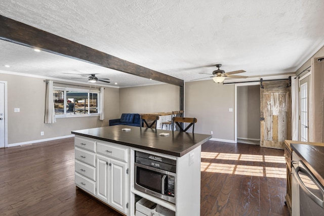 kitchen featuring white cabinetry, a barn door, dark hardwood / wood-style flooring, and beam ceiling