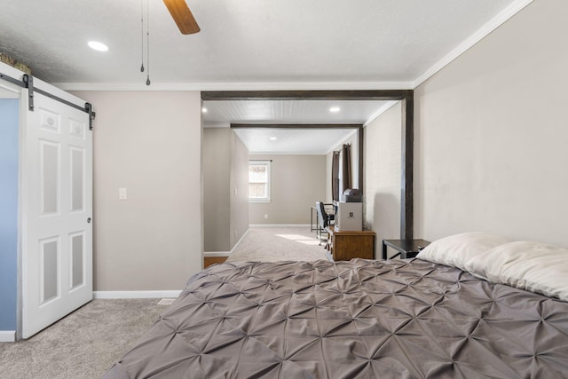 carpeted bedroom with ornamental molding, a barn door, and ceiling fan