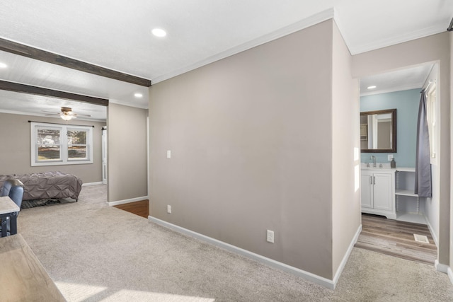 carpeted bedroom featuring crown molding, ensuite bath, beam ceiling, and sink