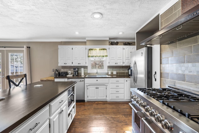 kitchen featuring white cabinetry, wall chimney range hood, decorative backsplash, and stainless steel appliances