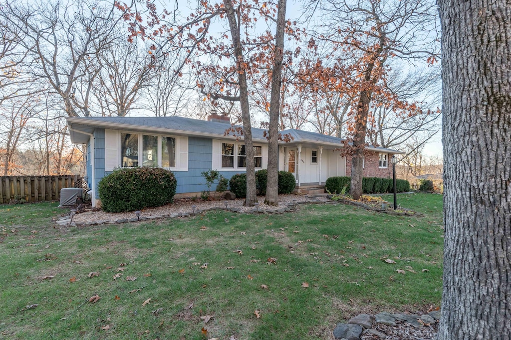 ranch-style house with central AC unit and a front yard