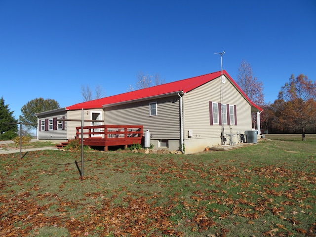 view of side of home with central AC unit, a deck, and a lawn