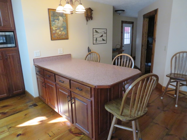 kitchen featuring a breakfast bar area, a chandelier, dark hardwood / wood-style flooring, kitchen peninsula, and pendant lighting