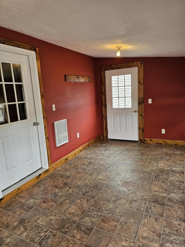 entryway with heating unit and a textured ceiling