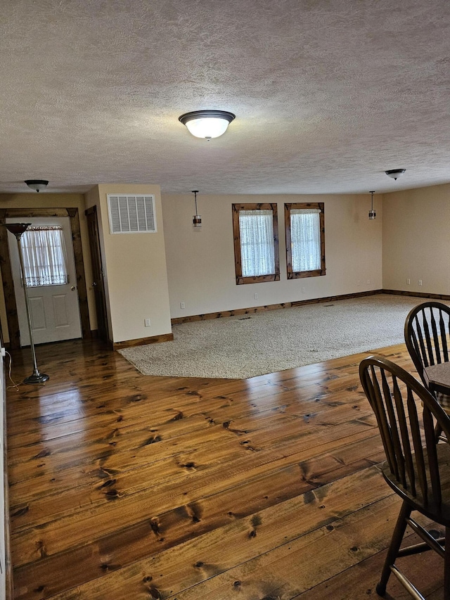 foyer entrance featuring a textured ceiling, dark wood-type flooring, and a healthy amount of sunlight