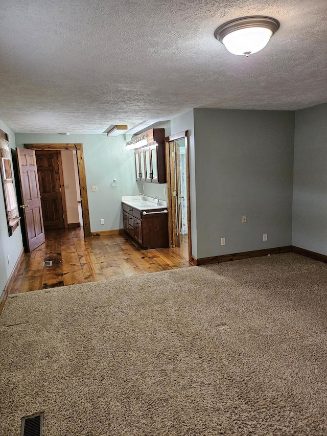 unfurnished bedroom featuring light carpet, a textured ceiling, and ensuite bath