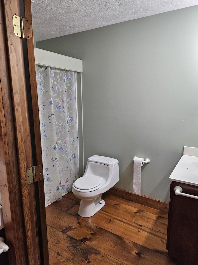 bathroom with wood-type flooring, vanity, a textured ceiling, and toilet