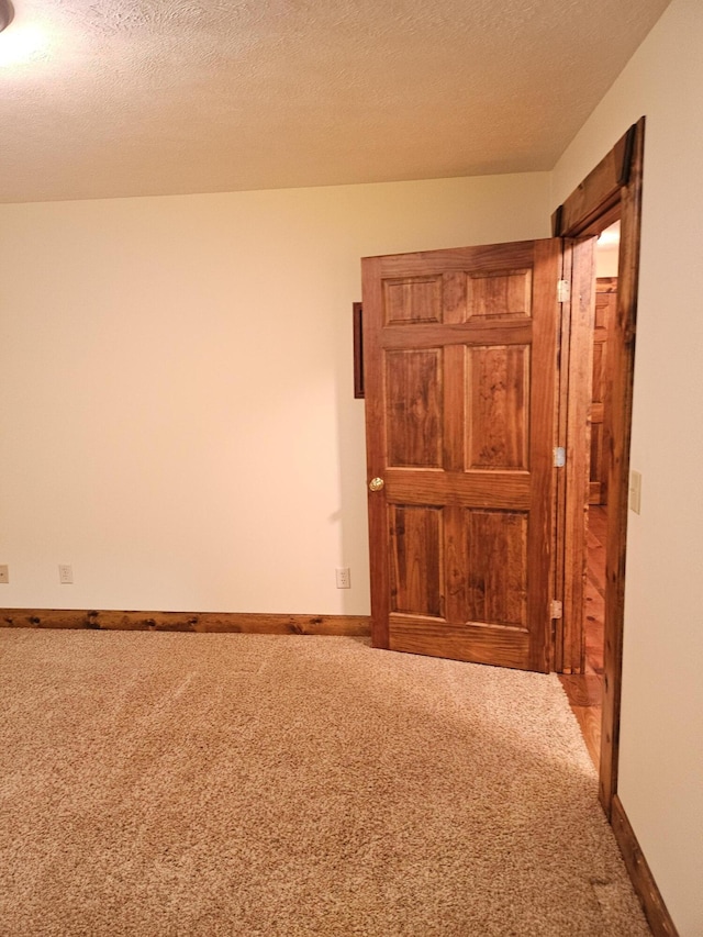 carpeted empty room featuring a textured ceiling