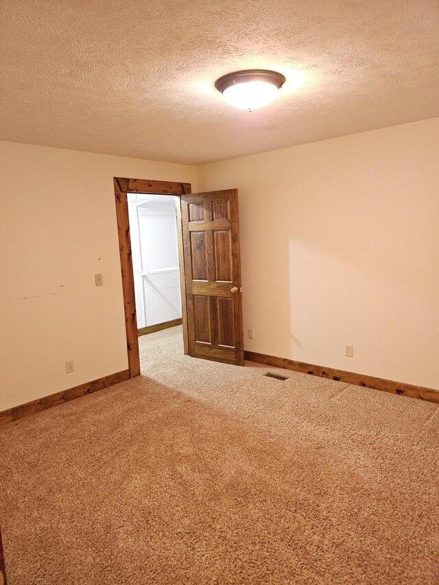 carpeted spare room with a textured ceiling