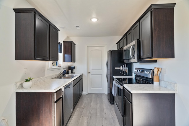 kitchen featuring dark brown cabinetry, appliances with stainless steel finishes, light hardwood / wood-style floors, and sink