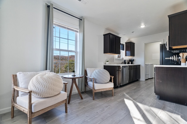 kitchen featuring washer and dryer, light wood-type flooring, and stainless steel appliances