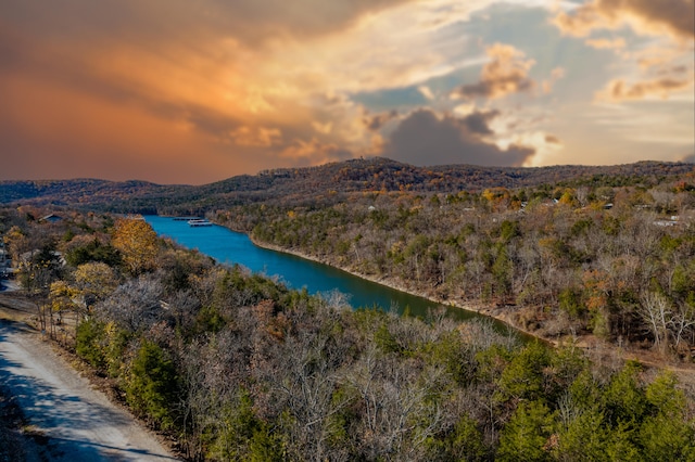 aerial view at dusk featuring a water and mountain view