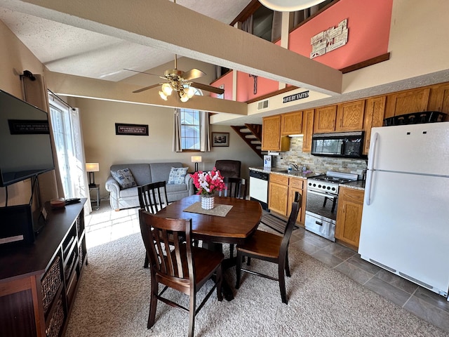 dining space with dark colored carpet, ceiling fan, a towering ceiling, a textured ceiling, and beamed ceiling