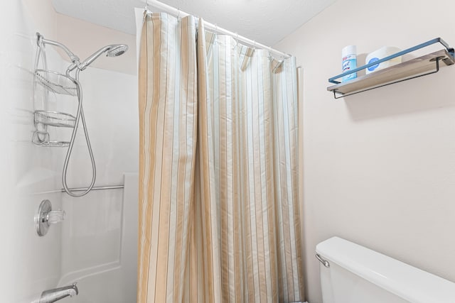 bathroom with a shower with shower curtain, toilet, and a textured ceiling