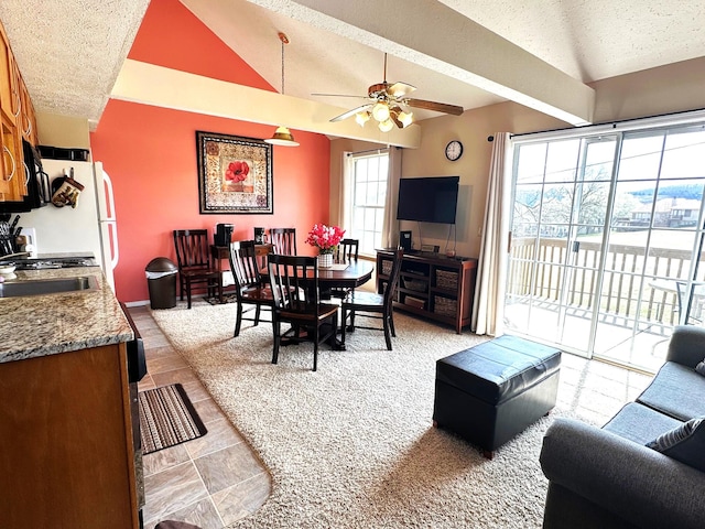 living room with vaulted ceiling with beams, ceiling fan, sink, and a textured ceiling