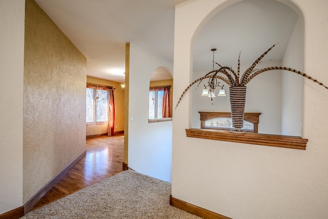 corridor with hardwood / wood-style floors and a chandelier