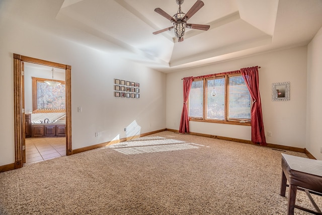 empty room with a tray ceiling, ceiling fan, and light colored carpet