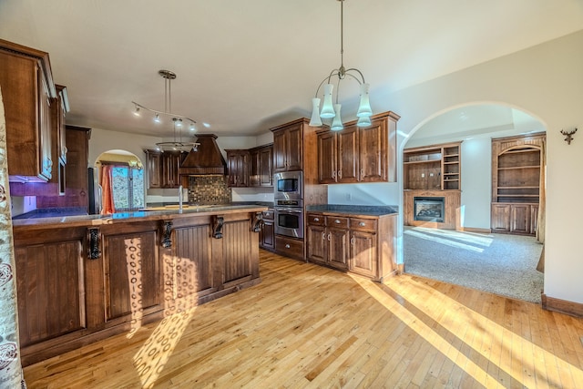 kitchen with appliances with stainless steel finishes, light wood-type flooring, a kitchen breakfast bar, decorative light fixtures, and an inviting chandelier