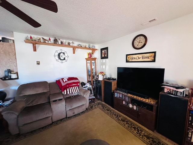 living room featuring ceiling fan and a textured ceiling