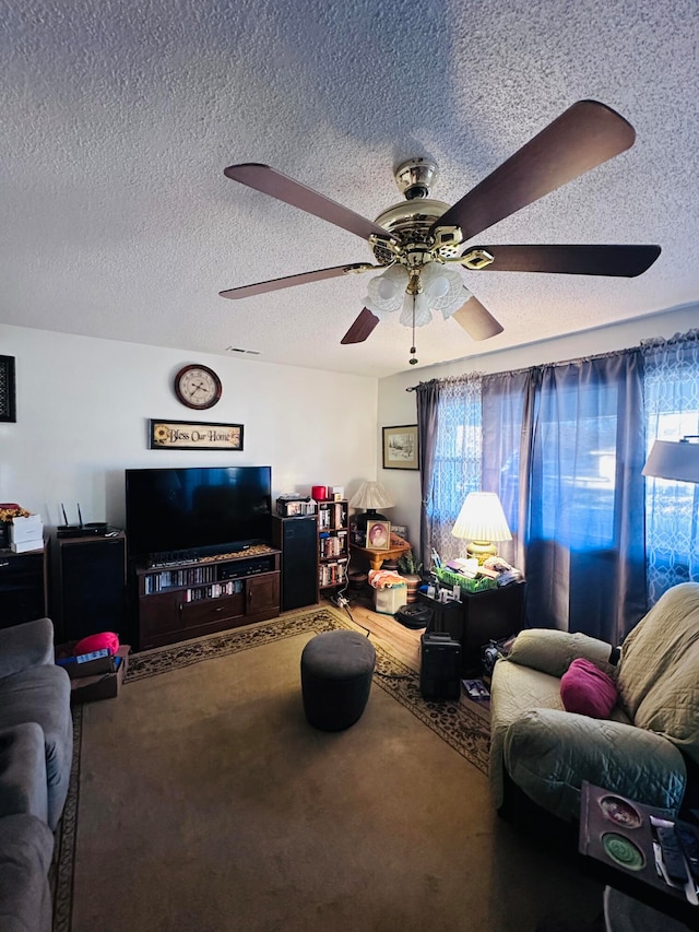 living room featuring carpet flooring, a textured ceiling, and ceiling fan