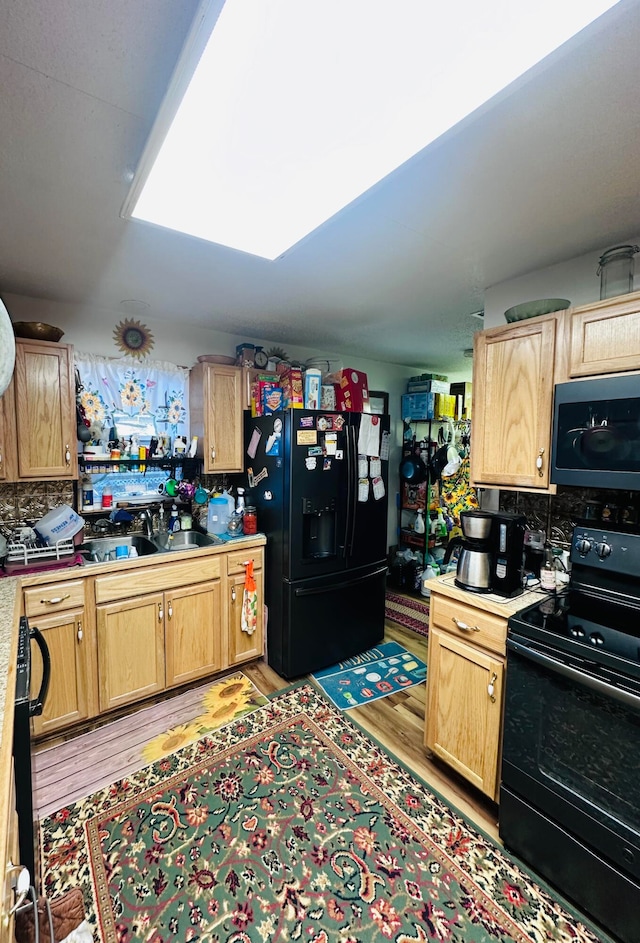 kitchen featuring sink, backsplash, light hardwood / wood-style flooring, and black appliances