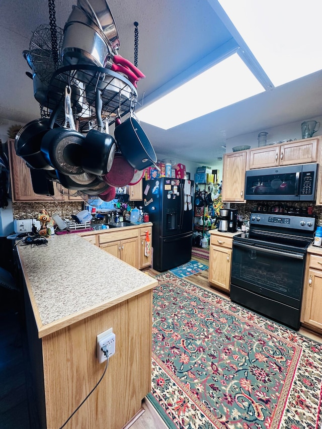 kitchen with light brown cabinetry and black appliances