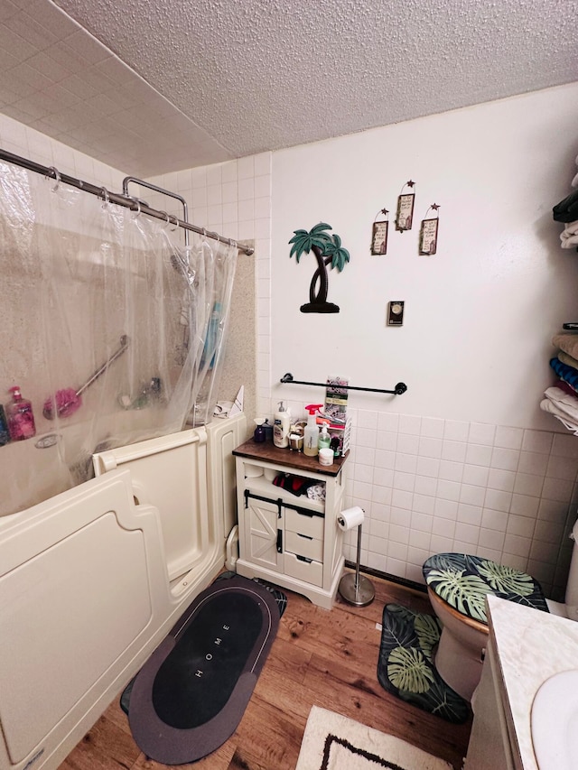 bathroom with hardwood / wood-style floors, vanity, tile walls, a textured ceiling, and shower / tub combo with curtain