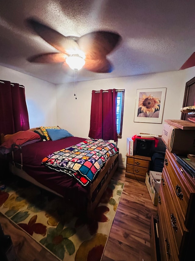 bedroom featuring a textured ceiling, ceiling fan, and dark wood-type flooring